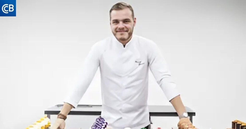 a chef standing in front of a table full of cakes